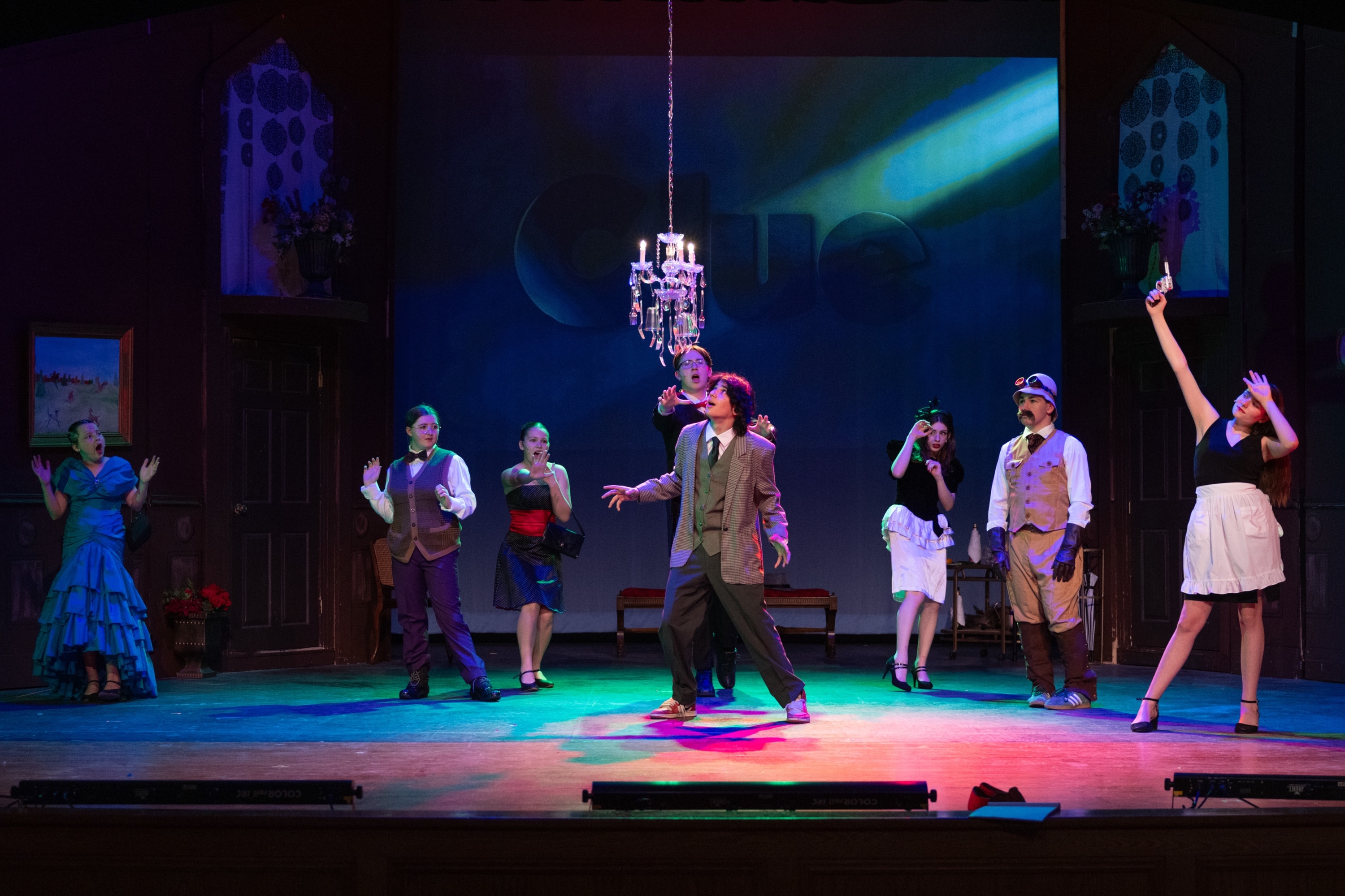Stage cast performing under theatrical lighting